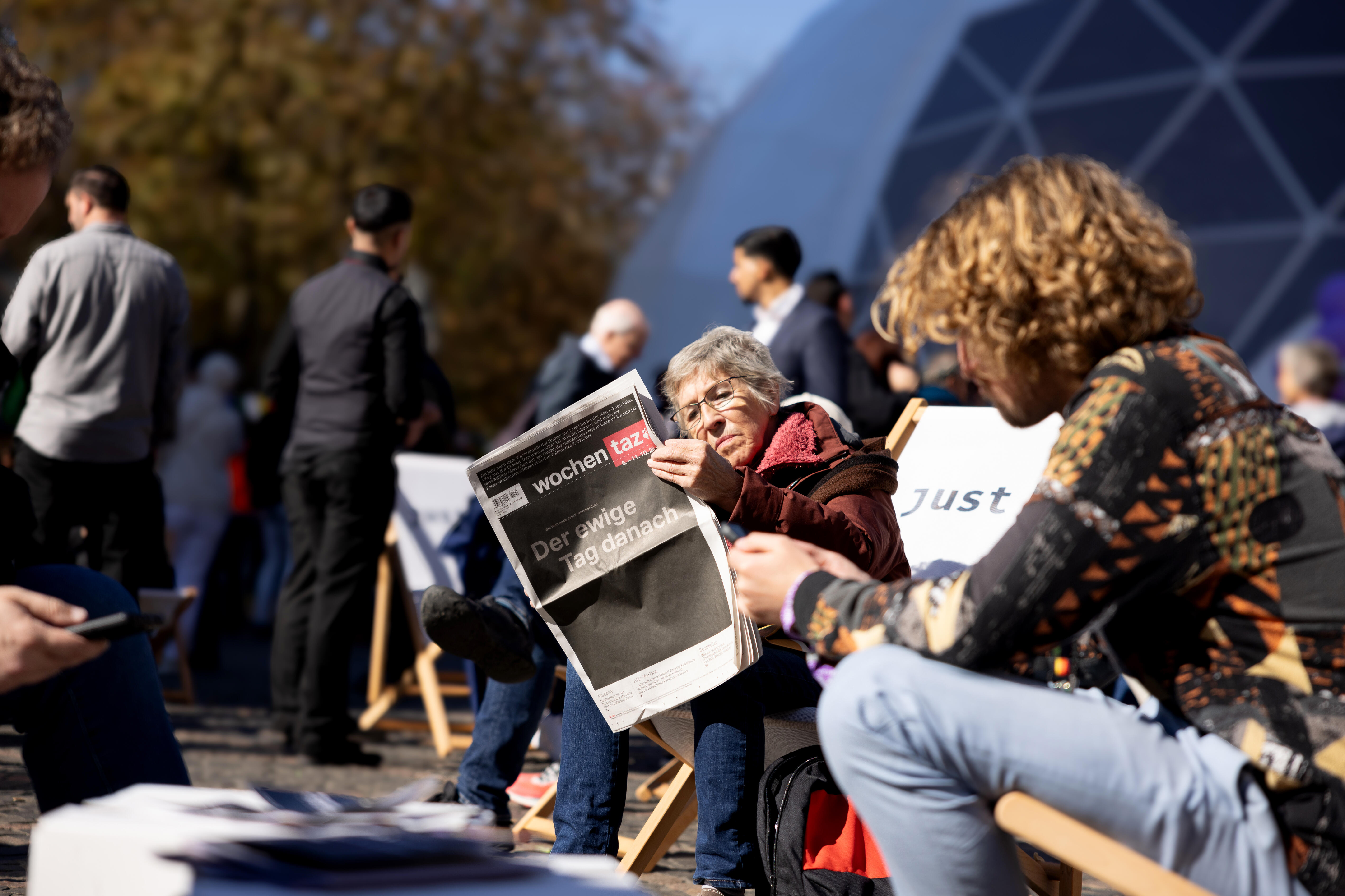 Besucherin liest Zeitung im Liegestuhl auf dem Münsterplatz, im Hintergrund das Lila Zelt