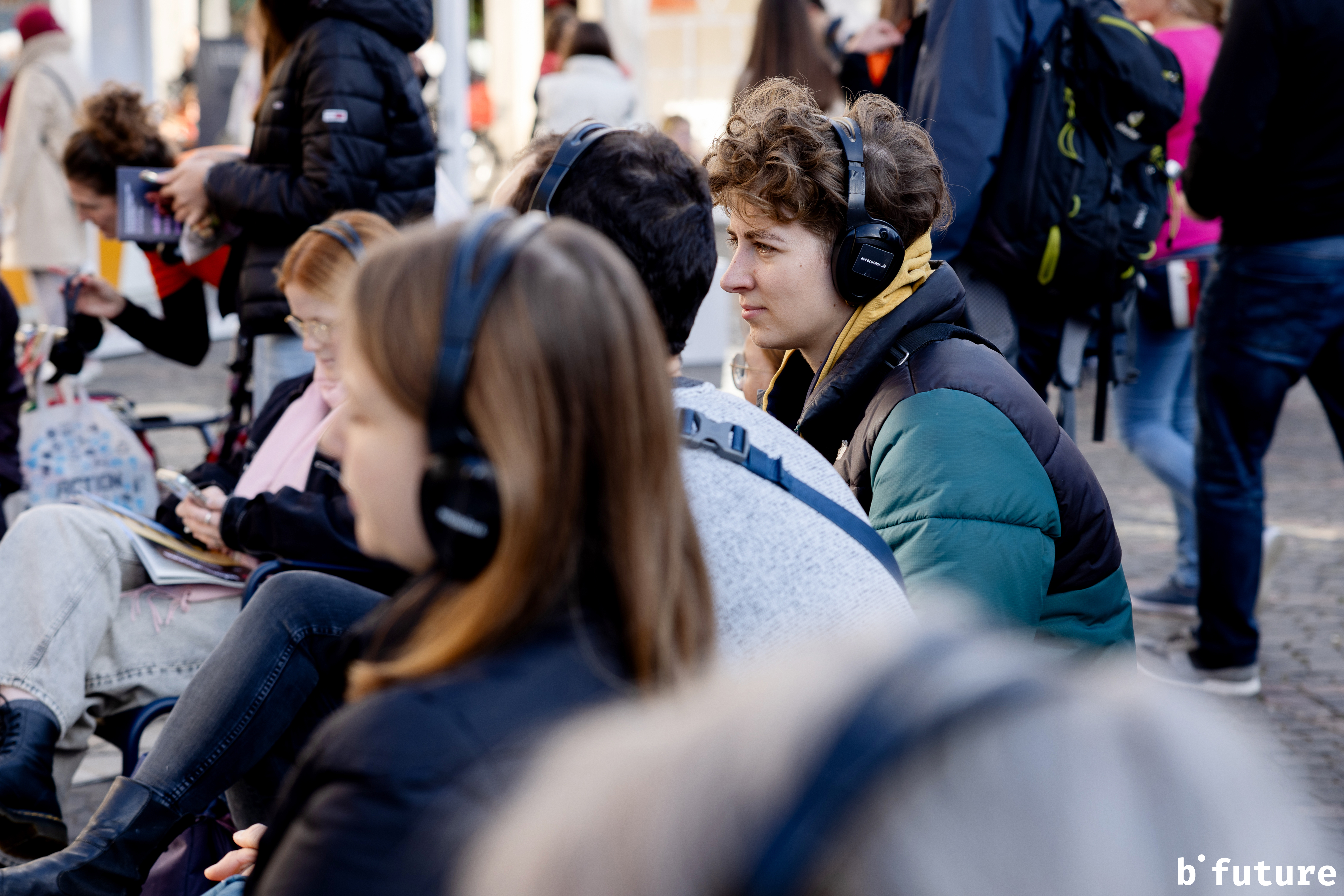 Menschen sitzen mit Kopfhörern vor dem Podcasthouse auf dem Münsterplatz.